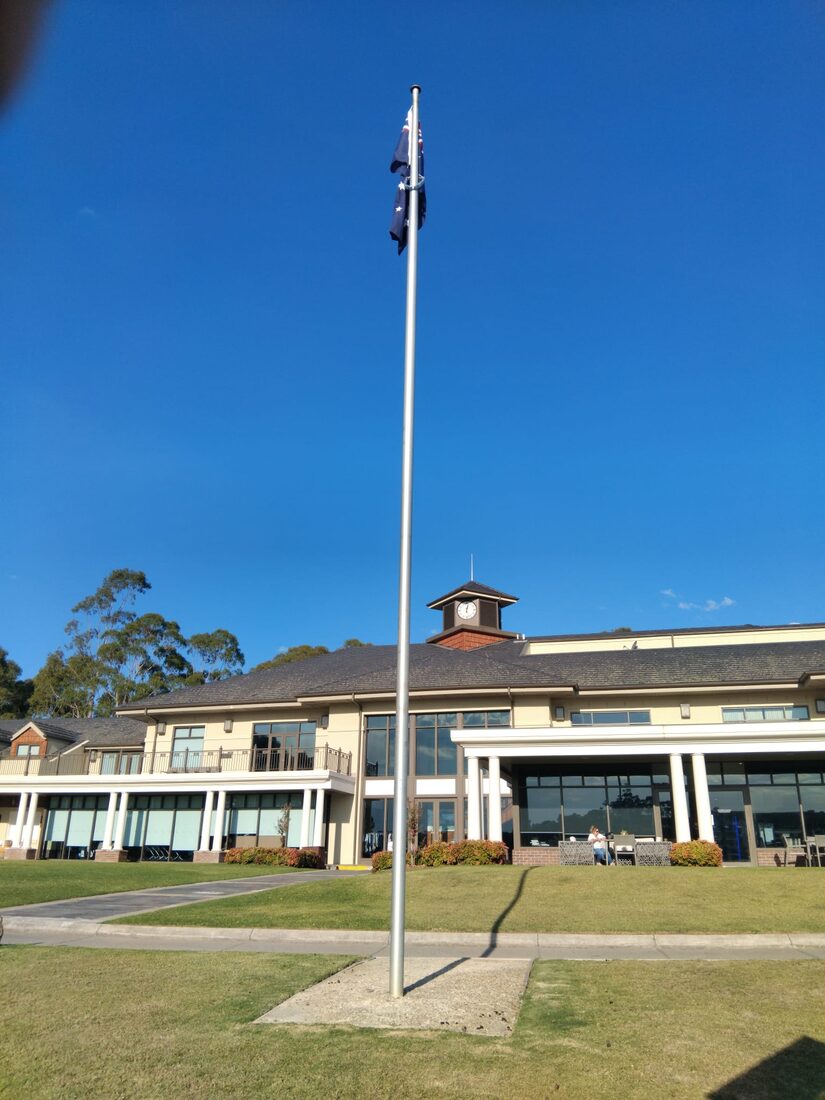 A tall flagpole flying the Australian flag outside a clubhouse