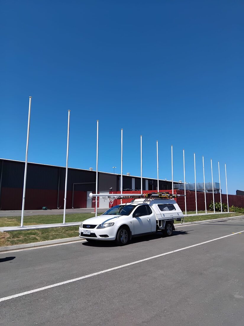 A row of white flagpoles installed outside a commercial depot