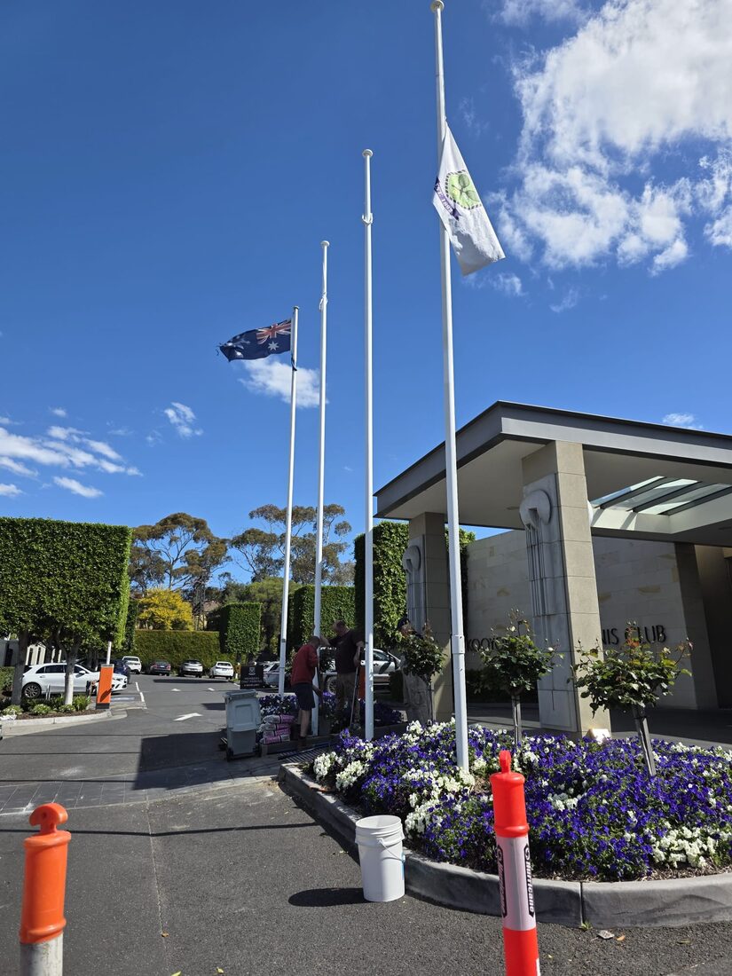 Flagpoles being installed at the entrance of a tennis club